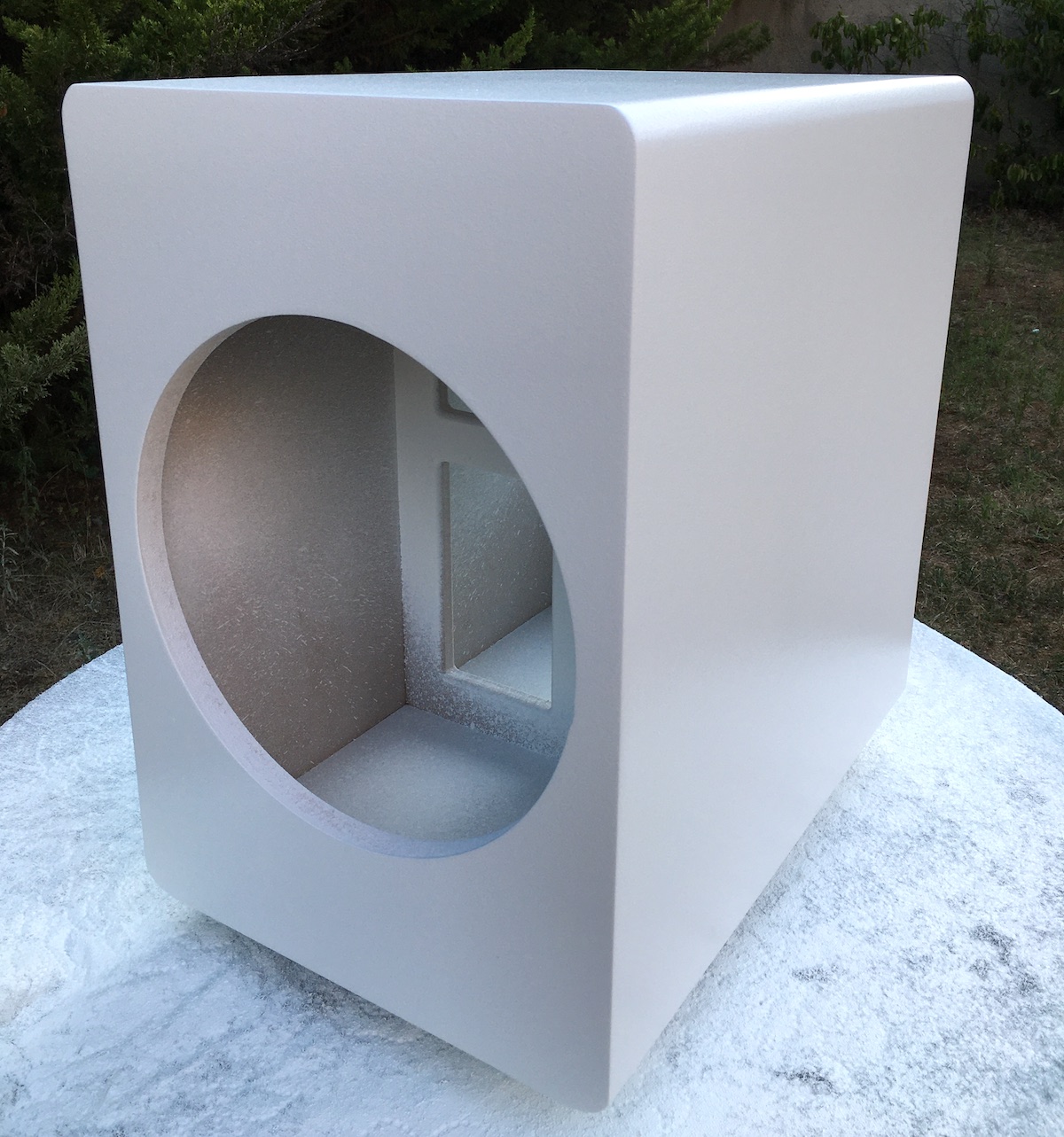 A dual opposed subwoofer box painted white with a paint gun.